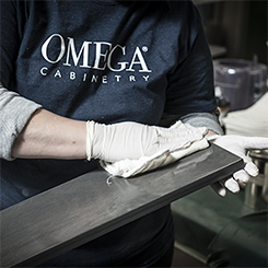 An Omega production associate applying a stain