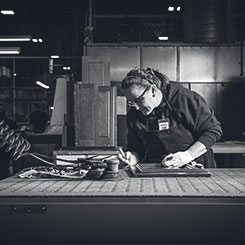 An Omega production associate working on the detailing of a cabinet door