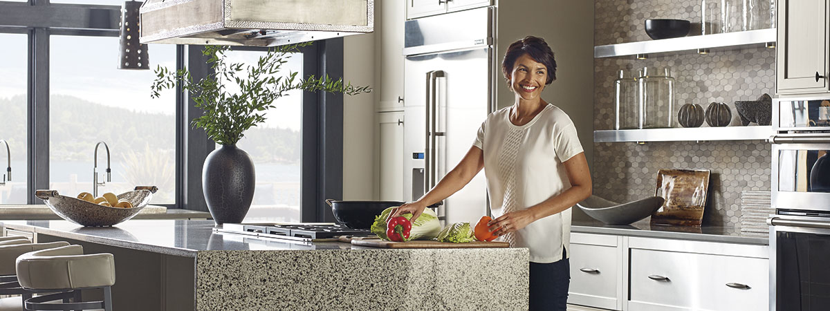 A woman preparing food at the island of her Omega kitchen